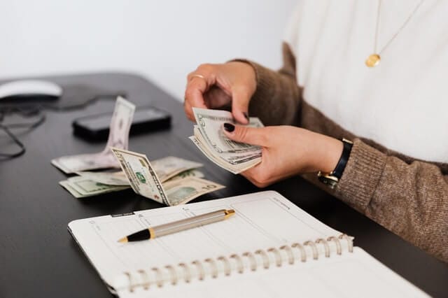 Bookkeeping & Financial Reporting A bookkeeper counting cash and recording transactions in a ledger for small business bookkeeping